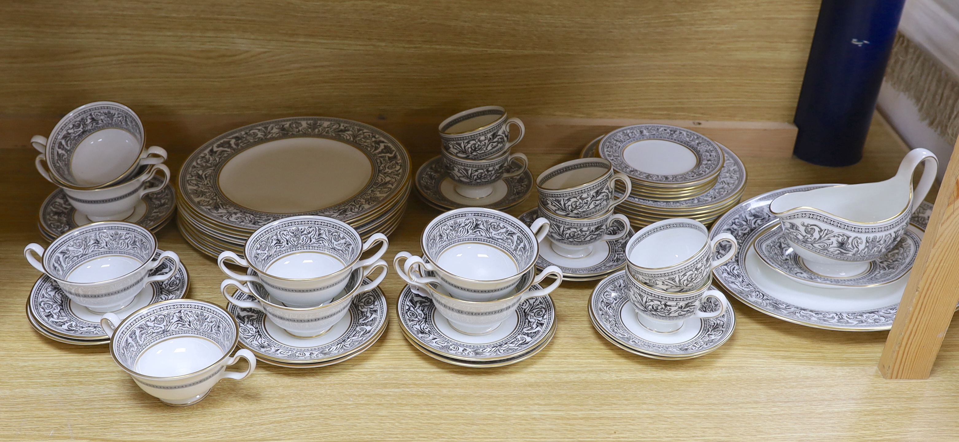 A Wedgwood Florentine part dinner set including twin handled cups, oval platter and dinner plates, largest 34cm wide